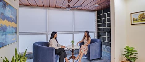 Una habitación con dos sillones azules, una pequeña mesa redonda y un ventilador de techo.