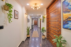A hallway with a polished marble floor, wooden paneling on one wall, and hanging plants. - FabHotel Havenora - Nr. Maharani Bagh (New Delhi)