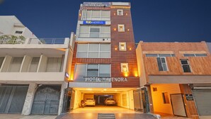 A multi-story hotel with a modern facade, a prominent 'HOTEL HAVENORA' sign, and a covered parking area with two cars. - FabHotel Havenora - Nr. Maharani Bagh (New Delhi)