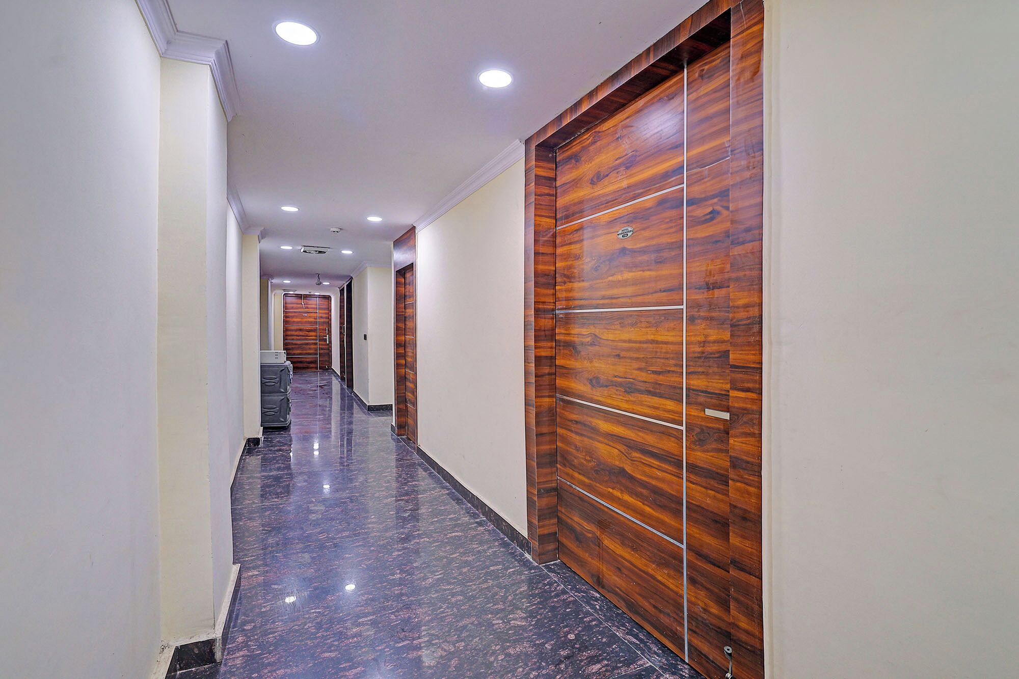 A hallway with wooden doors and a polished marble floor.