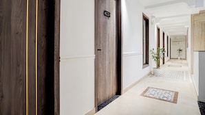 A hotel corridor with wooden doors, a potted plant, and a tiled floor. - FabHotel Amrit luxury Inn by Amrit Residency (Gurugram)