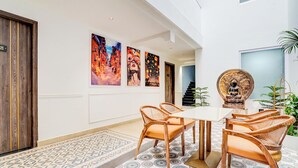 A dining area with a white table and wooden chairs, surrounded by patterned floor tiles and artwork on the walls. - FabHotel Amrit luxury Inn by Amrit Residency (Gurugram)