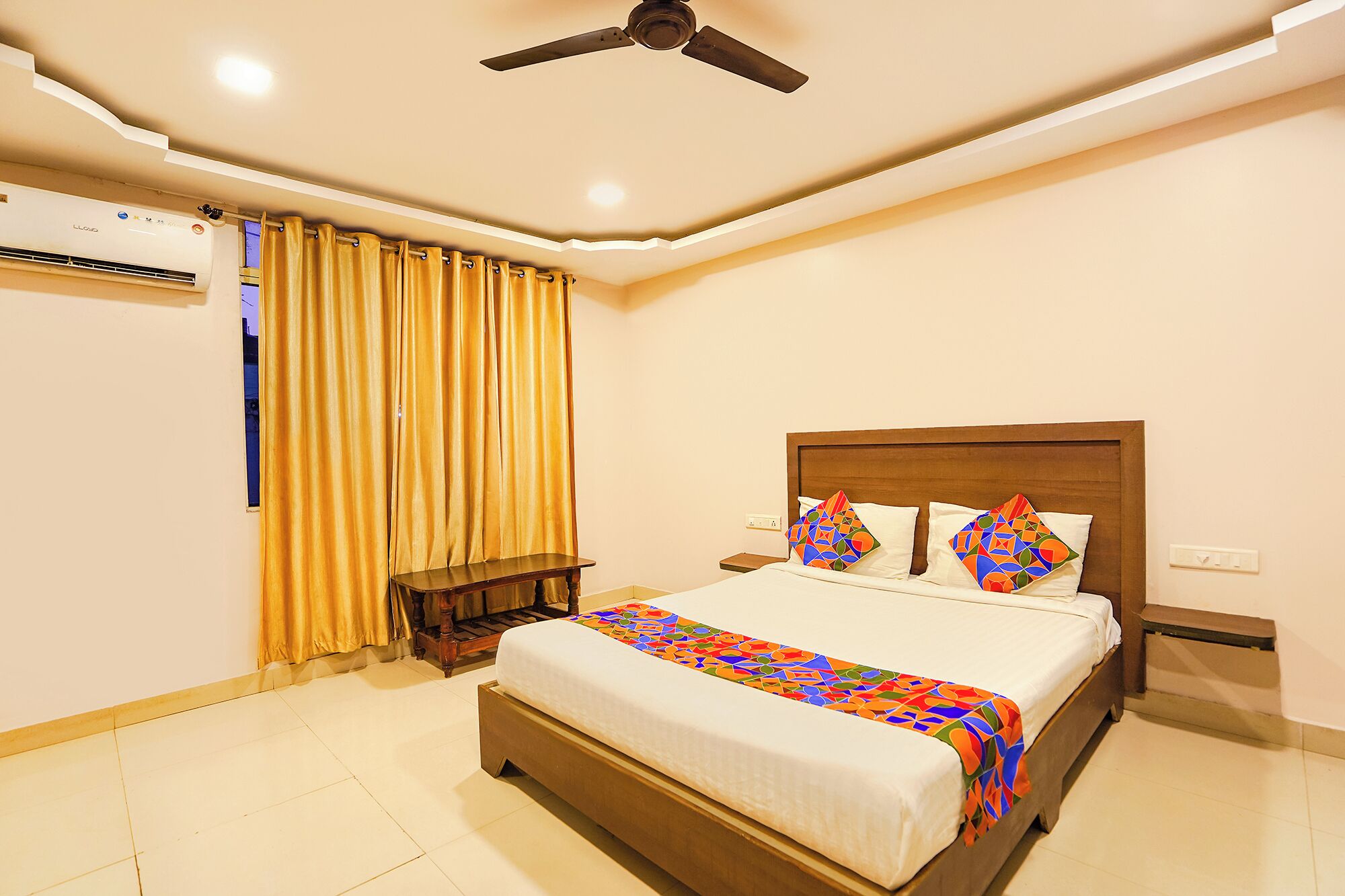 A neatly arranged bedroom with a bed, curtains, a ceiling fan, and an air conditioning unit.