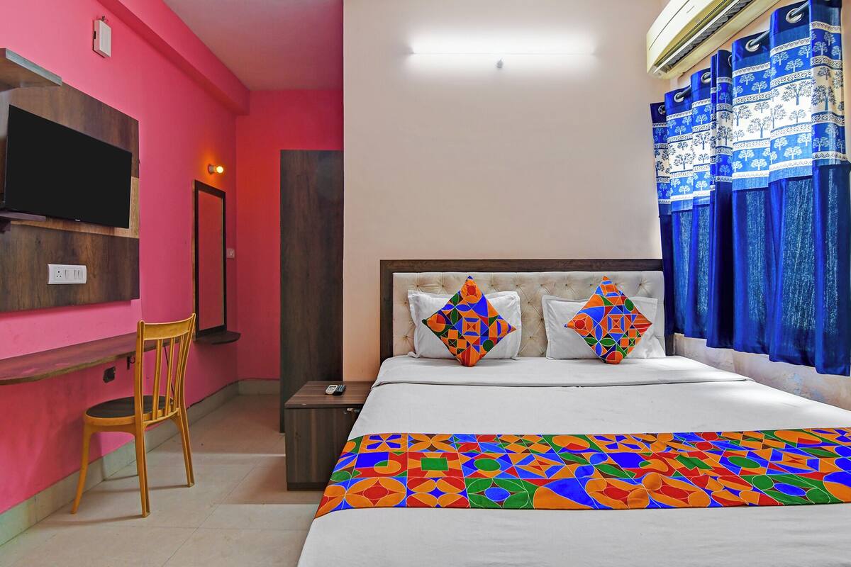 A hotel room with a bed, a TV, a chair, and a desk.