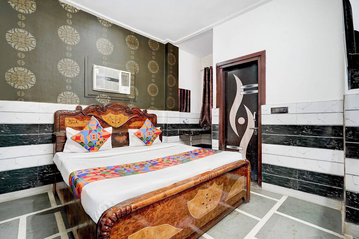 A bedroom with a wooden bed, patterned wallpaper, a large mirror, and a modern door.
