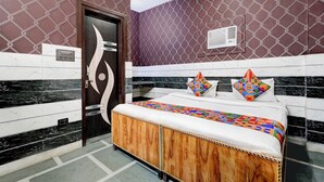 A hotel room with a bed, a door, and a wall with a geometric pattern. - Fabhotel Happy Stay I (Noida)