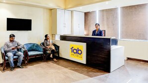 Een receptie met een receptiebalie met de tekst 'fab hotels', twee stoelen en een televisie aan de muur.