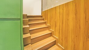 A wooden staircase with a green wall on one side and a wooden panel on the other. - Via Woodlands (Mumbai)