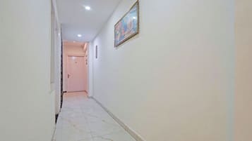 A hallway with a tiled floor, a door at the end, and a framed picture on the wall.