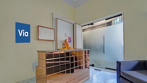 A reception area with a tiled counter, a refrigerator, a sofa, and a 'Via' sign on the wall. - Via Crown DX (New Delhi)
