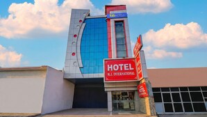A modern hotel building with a prominent facade, a large glass window, and a sign indicating it is M.J. International Hotel. - Fabhotel Mj International (Lucknow)