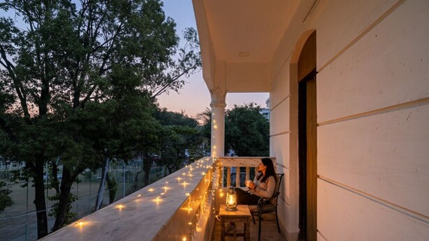 A balcony with string lights, a lantern, and a person sitting at a table. - Fabhotel Springwood (Barasat)