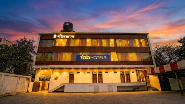 Een modern hotel met een bord waarop 'fabHOTELS' staat en een bord in de lokale taal boven de ingang.