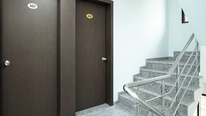 Eine Doppeltür mit den Zimmernummern 301 und 302, eine Treppe mit Metallgeländern und eine helle Wand.