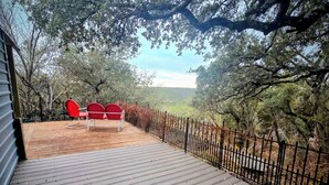 Un pontile in legno con due sedie rosse e un recinto metallico.