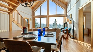 A spacious dining area with a high ceiling and large windows, wooden flooring, and modern furniture. - The Birches on Marbles Way | Snowmobile Access | Waterfront Access on Rangeley Lake (Rangeley)