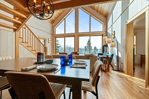 A spacious dining area with a high ceiling and large windows, wooden flooring, and modern furniture. - The Birches on Marbles Way | Snowmobile Access | Waterfront Access on Rangeley Lake (Rangeley)