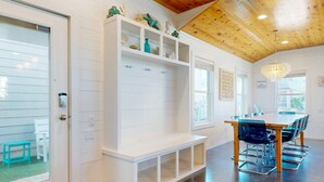 Ein modernes Interieur mit Holzboden, weißen Wänden, einem Essbereich mit Tisch und Stühlen sowie einer eingebauten Sitzbank mit Regalen.