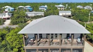 Un edificio de varios pisos con techo plano, grandes ventanales y un balcón con mobiliario exterior.