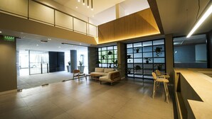 A spacious lobby with a reception desk, seating area, and large windows with plants. - BAH Independencia By iPPA (Buenos Aires)