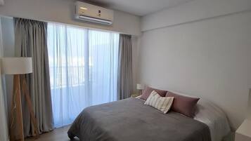 Een moderne hotelkamer met een groot bed, een staande lamp en een airconditioning.