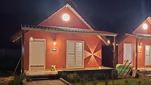 Una hilera de dos edificios con techo rojo, puertas y ventanas blancas, cada uno con un pequeño porche y una lámpara sobre la puerta.