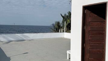 A building with a large open patio, a wooden door, and a view of the sea.