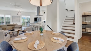 Een moderne woonkamer met een ronde eettafel, banken en een trap.