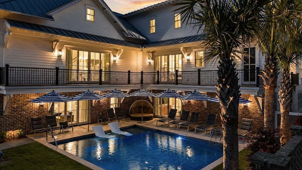 Een tweelaags huis met een zwembad, buitenmeubilair en een balkon.