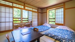 A traditional Japanese room with tatami flooring, a low table, two tatami beds, and sliding doors. - Onsen Oyado Ruribitaki (Matsumoto)
