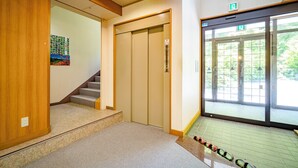 A hotel lobby with a wooden door, a staircase, and a large glass door leading outside. - Onsen Oyado Ruribitaki (Matsumoto)