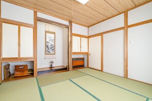 A traditional Japanese room with tatami flooring, sliding doors, and a wooden ceiling. - Onsen Oyado Ruribitaki (Matsumoto)