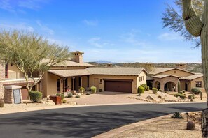 A residential area with houses featuring arched doorways, a garage, and a well-maintained lawn with cacti.