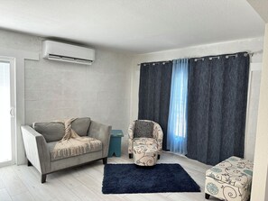 A living room with a grey sofa, a patterned armchair, a small side table, and a dark rug. - 3BR Coastal Getaway with Large Yard & BBQ near Anna Maria Island (Bradenton)