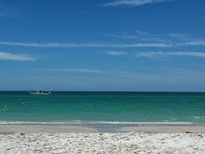 Una platja amb un vaixell a l'aigua i un tram de sorra.