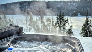 A hot tub with a view of a snowy landscape and trees.
