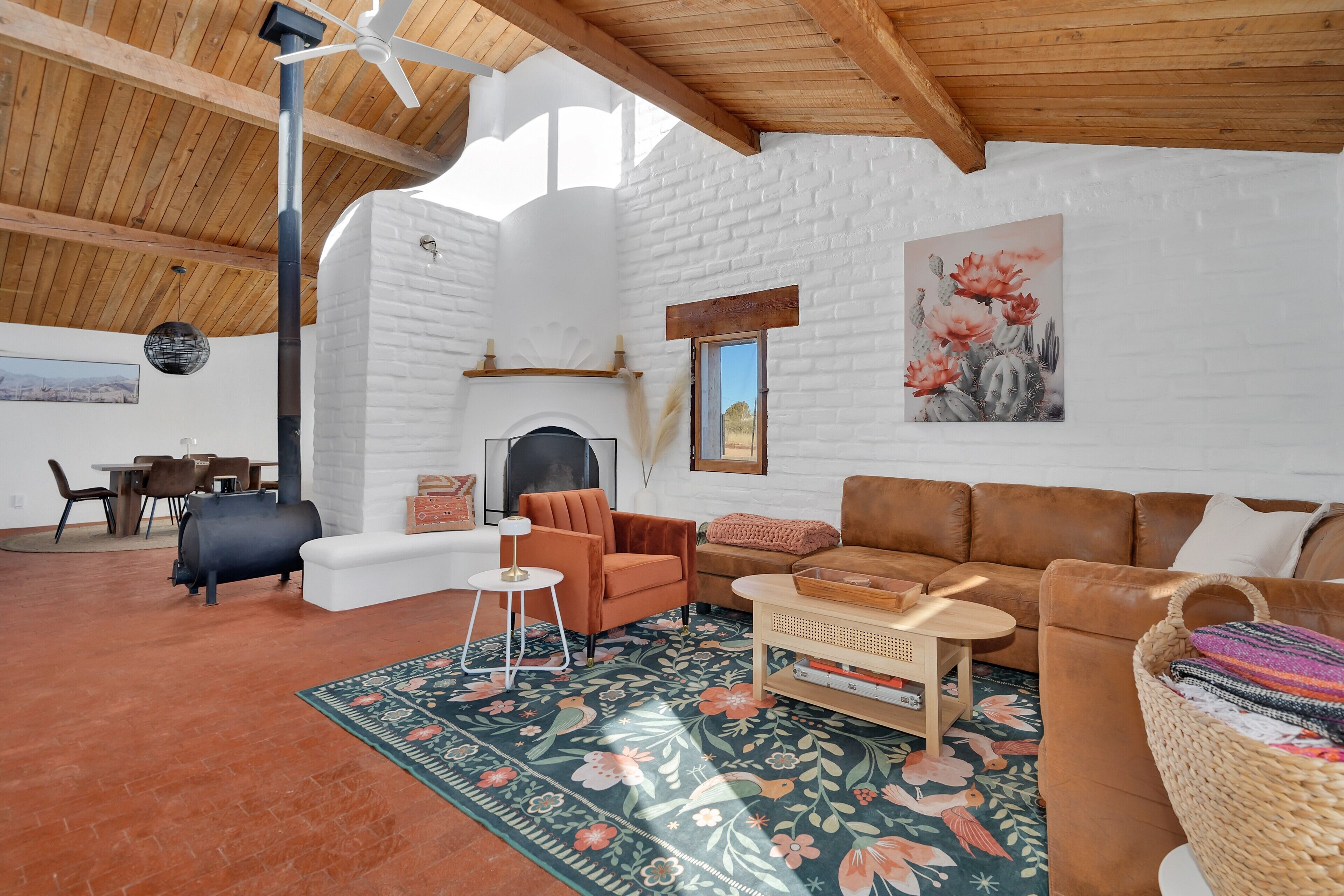 Ein gemütliches Wohnzimmer mit Kamin, einem braunen Ledersofa, einem Couchtisch und einer rustikalen Decke.