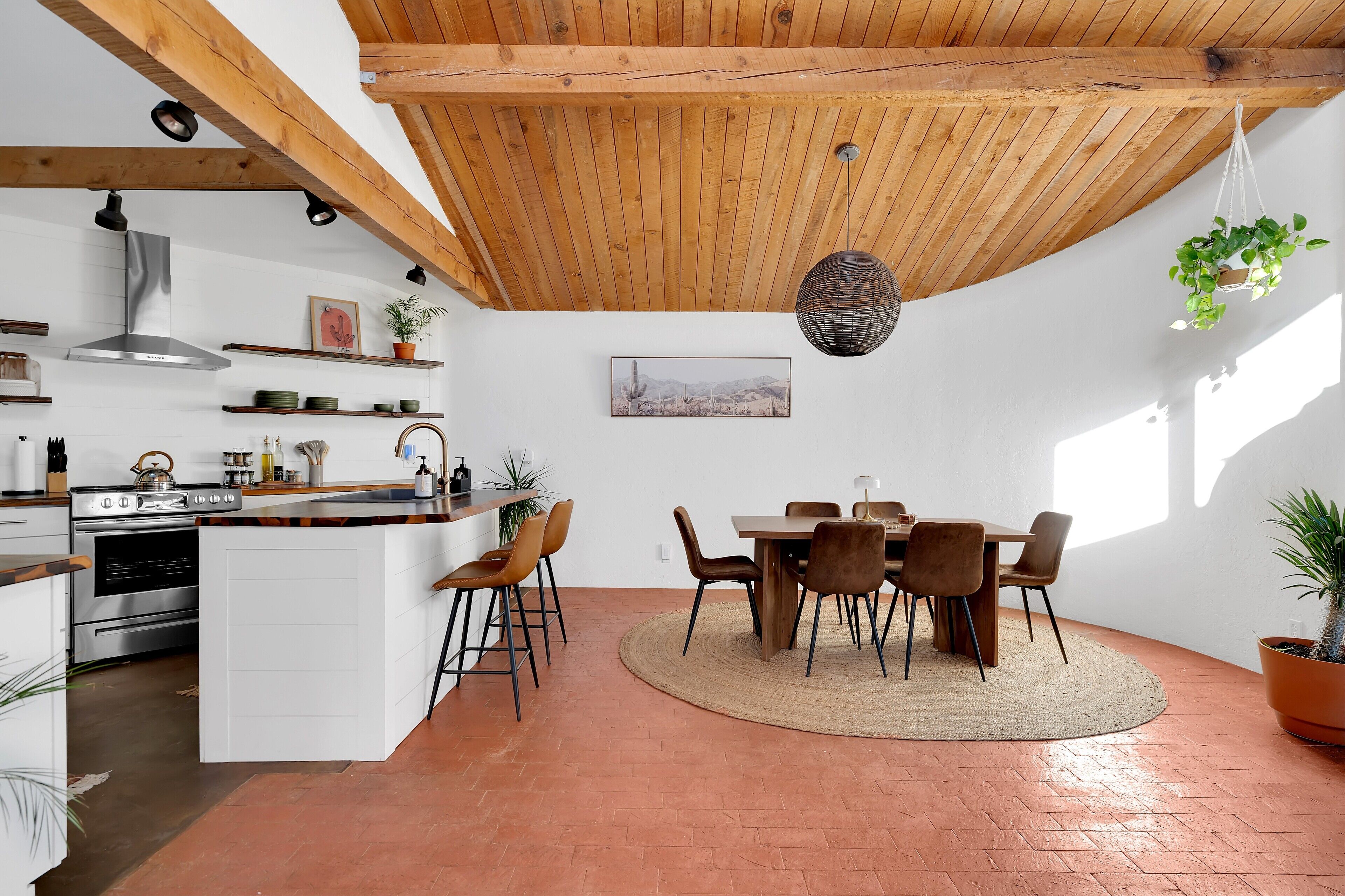 Een moderne keuken met witte kasten, een centraal eiland en een eethoek met een ronde tafel en stoelen.
