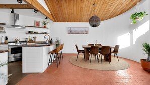 A modern kitchen with white cabinets, a central island, and a dining area with a round table and chairs. - Casa de Kiva - your Cochise County Escape (Cochise)