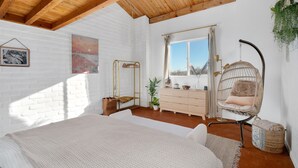 A bedroom with a bed, a hanging chair, a dresser, a window with curtains, and a plant. - Casa de Kiva - your Cochise County Escape (Cochise)