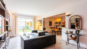 A spacious living area with a sofa, a glass coffee table, and a kitchen in the background. - le gîte jaune des gîtes de Bel-Air en Luberon (TAILLADES)