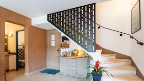 A staircase with a decorative railing, a kitchen area with a counter and cabinets, and a door leading to a bathroom. - le gîte jaune des gîtes de Bel-Air en Luberon (TAILLADES)