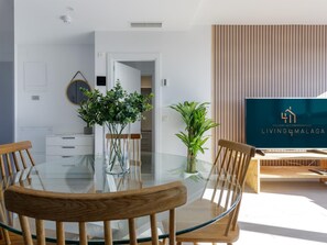 A modern dining area with a glass table, wooden chairs, and potted plants.
