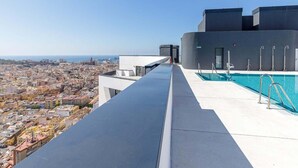 Una piscina sul tetto con vista sulla città, un edificio moderno e cielo sereno.