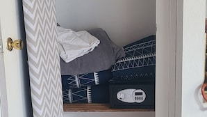 Une petite pièce fermée, équipée d’un lit, d’un portant à vêtements et d’un rideau de douche.