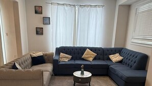 A living room with a beige sofa, a dark blue sectional sofa, and a round coffee table. - Short Term Cozy stay in beautiful Fergus (Fergus)