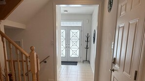 A hallway with a wooden staircase, a coat rack, and a door with a geometric glass pattern. - Short Term Cozy stay in beautiful Fergus (Fergus)