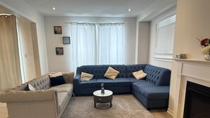 A living room with a beige sofa, a blue sectional sofa, a round coffee table, and a fireplace. - Short Term Cozy stay in beautiful Fergus (Fergus)