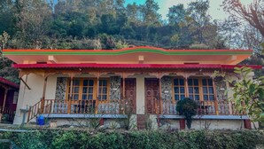 Un bâtiment traditionnel avec un toit rouge, des portes en bois et une façade en pierre.