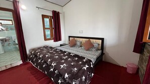 Une chambre à coucher avec un lit, une fenêtre avec des rideaux, une petite table et une poubelle.